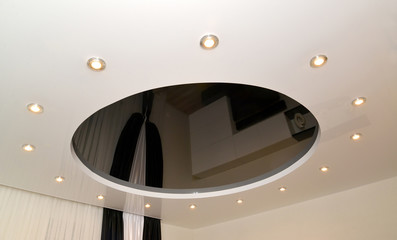 Glossy stretch ceiling with an oval design and dot lamps