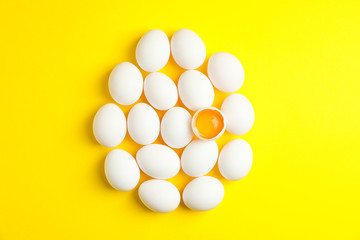 Flat lay composition with chicken eggs on yellow background, space for text