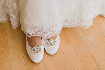 Closeup of a caucasian bride put on her white shoes.