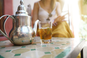 Close up of traditional Moroccan min ttea with girl in background