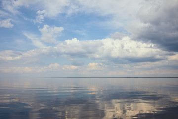 Calm pond and light blue sky with white clouds