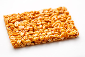 A large tile of roasted peanuts bar in a sweet molasses on a white background. Kozinaki useful and tasty sweets of the East