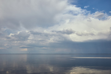 Peaceful blue sky with white clouds reflected in river water