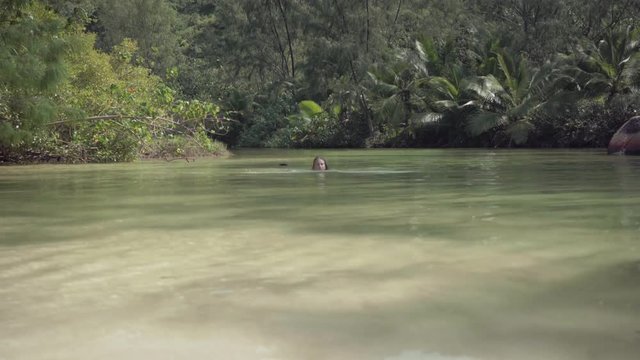 Seychelles. Praslin Island. The girl swims in the water on an exotic island in the Indian Ocean. Paradise on Earth. Tourism, relax, vacation, travel concept.