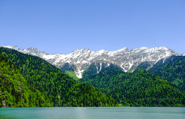 View of lake Ritsa (Riza) in Abkhazia in the spring, in the background snow-capped mountains