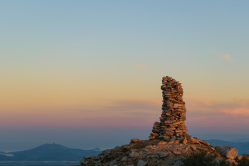 Mountain peak stone pile at sunset