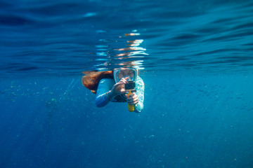 Woman making photo underwater. Girl snorkeling in full-face mask. Snorkel with fish under water...