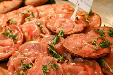 Traditional delicious salted smoked sliced salmon with black bread, old city market hall in Helsinki, Finland 