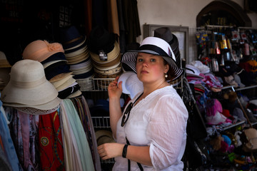 Woman measuring а hat on a street market.