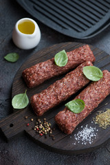 Close-up of fresh uncooked marbled beef kabobs with seasonings on a wooden cutting board, studio shot