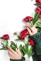 Creative composition. Beautiful female hand with red flowers on white background. Cosmetics for hands anti wrinkle.Top view, copy space
