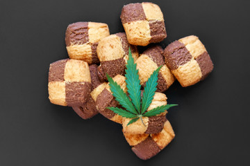 Hemp biscuits on a dark background with a green leaf of cannabis. Marijuana CBD dessert. Copy space. View from above