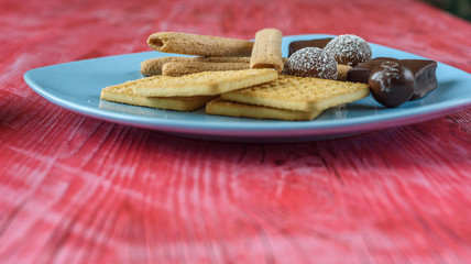 Homemade pastries and chocolates on a ceramic plate on a wooden background.