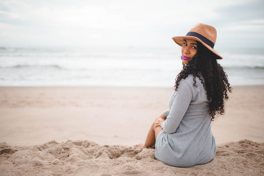 selective focus photo of woman sitting on beach sand