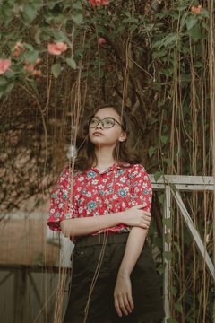 woman wearing red floral blouse standing near tree