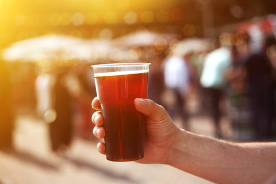 Man holding a jar of dark beer in his hand at the beer and food street festival