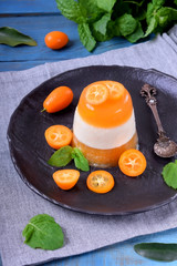 Layered dessert with fruits and yogurt on the black plate surrounded by kumquats and mint