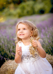 little girl in white dress sitting on hay