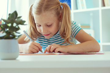 Portrait of schoolgirl at classroom writing at the table