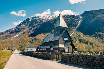 Roldal Stave Church (Roldal stavkyrkje) with snow cap mountains background, Norway autumn in the village
