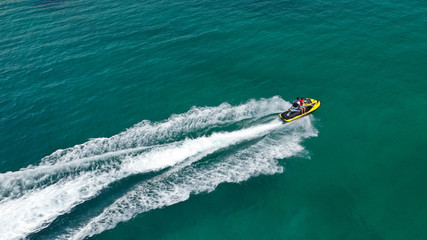 Fototapeta premium Aerial drone top view photo of jet ski cruising in high speed in emerald exotic tropical bay