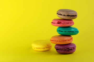 Sweet french macaroons cake on the yellow background.
