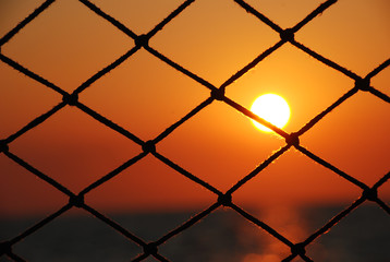 Fototapeta premium View of the sunset through the net of sailboat.