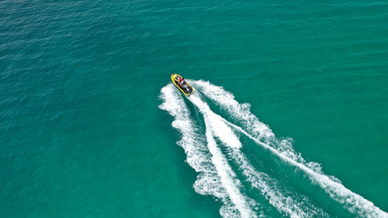 Aerial drone top view photo of jet ski cruising in high speed in emerald exotic tropical bay