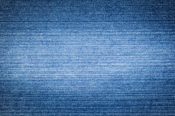 Texture of blue jeans with a light white stripe in the middle of the denim for the background. Horizontal cotton fiber jeans.