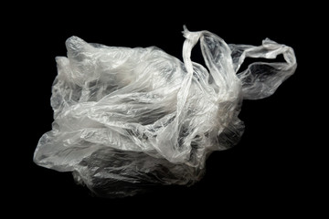 Fototapeta premium Plastic bag with handles on a black background isolate. Used plastic bag for recycling. Recycling of plastic waste into pellets as a business.