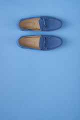 Blue suede man's mocassin shoes over blue background
