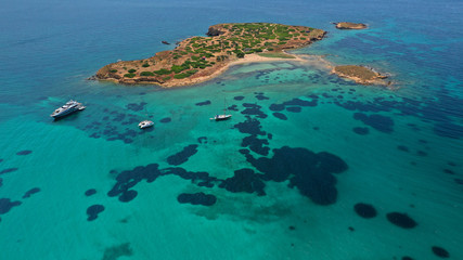 Aerial drone bird's eye view of small islet of Ydrousa with turquoise and sapphire clear waters and only one mile distance from coast in Voula, Athens riviera, Attica, Greece