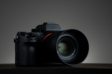 Mirrorless photo camera on wood table isolated gray background