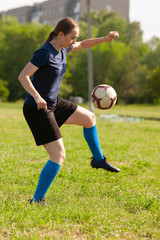 Young girl kicking soccer ball on field