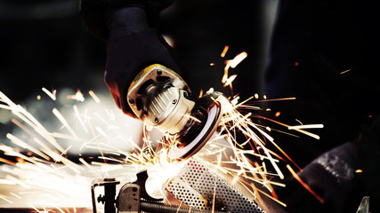 close up of a grinder machine cutting steel with metal sparks and dark black copy space background.