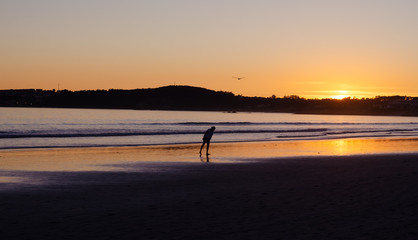 Woman looking at the sand on the beach of La Lanzada, O Grove, Pontevedra, Galicia, Spain. No people.