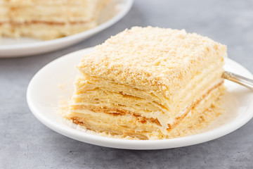 Layered cake with cream Napoleon millefeuille vanilla slice on a white plate.
