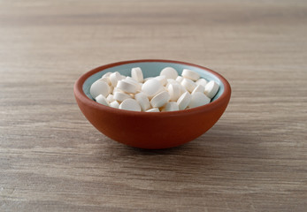Fototapeta na wymiar DHEA pills in a bowl on a table side view