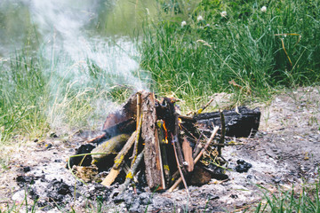 A fire is burned on the ground, and thick smoke rises to the top.