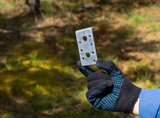A man's hand in a black work glove holding a construction corner bracket