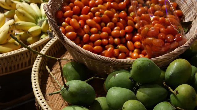 Fruits and vegetables on rustic stall. Assorted fresh ripe fruits and vegetables placed on rustic oriental stall in market. Green mango, tomatoes and yellow banana