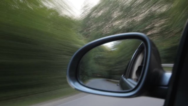 Fast driving on road, nature reflected on car mirror, time lapse, hurried to take all and miss everything
