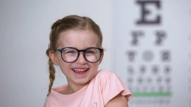 Joyous little girl in eyeglasses laughing, positive vision treatment results