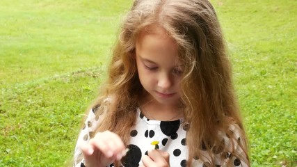 Sweet girl holds a chamomile and tears off the petals. Guessing on flower. Dreams of love
