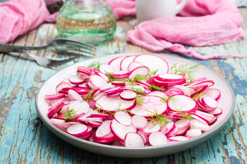 Fototapeta na wymiar Fresh salad of radish and dill on a plate on a wooden table