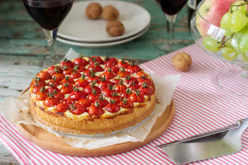 Tart, pie or cheesecake with cottage cheese and tomatoes, served with red wine on a wooden background.