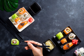 Various Fresh and delicious sushi set on white slate , hand with slate sticks, sauce on light stone background , flat lay