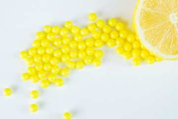 Vitamin C in two forms - natural and dragee. Half a lemon lies on a white background, next to pharmacological vitamins. Vitamin C has a wide range of positive health effects.