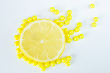 Vitamin C in two forms - natural and dragee. Half a lemon lies on a white background, next to pharmacological vitamins. Vitamin C has a wide range of positive health effects.