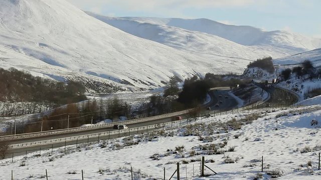 Freeflowing traffic, cars vans and HGVs on the M6 motorway near Tebay in Cumbria. The motorway is clear, though deep winter snow covers the Howgill fells of the far eastern Lake District 